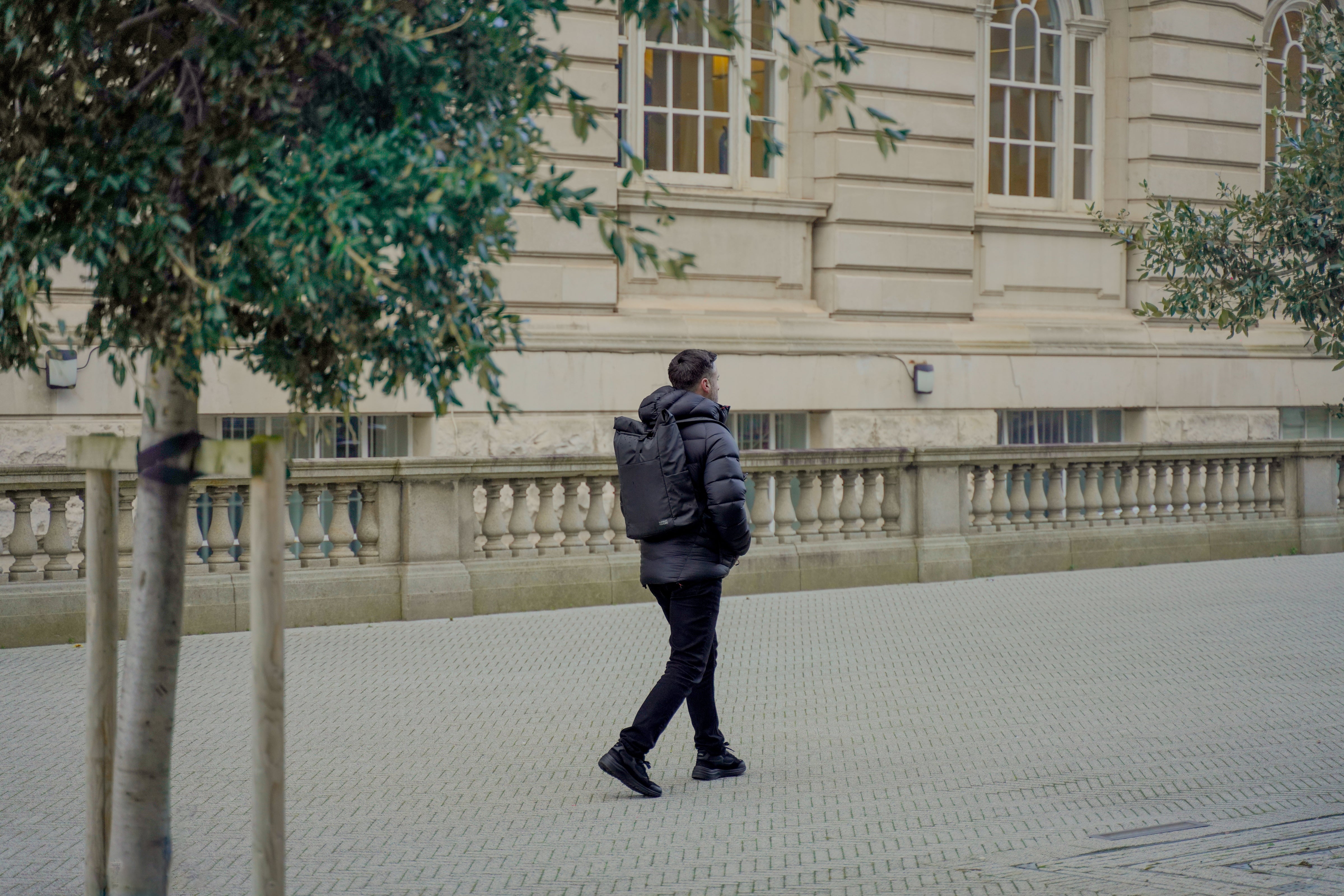 Man Walking through Leafy City with Summit and Shore Roll Top Backpack