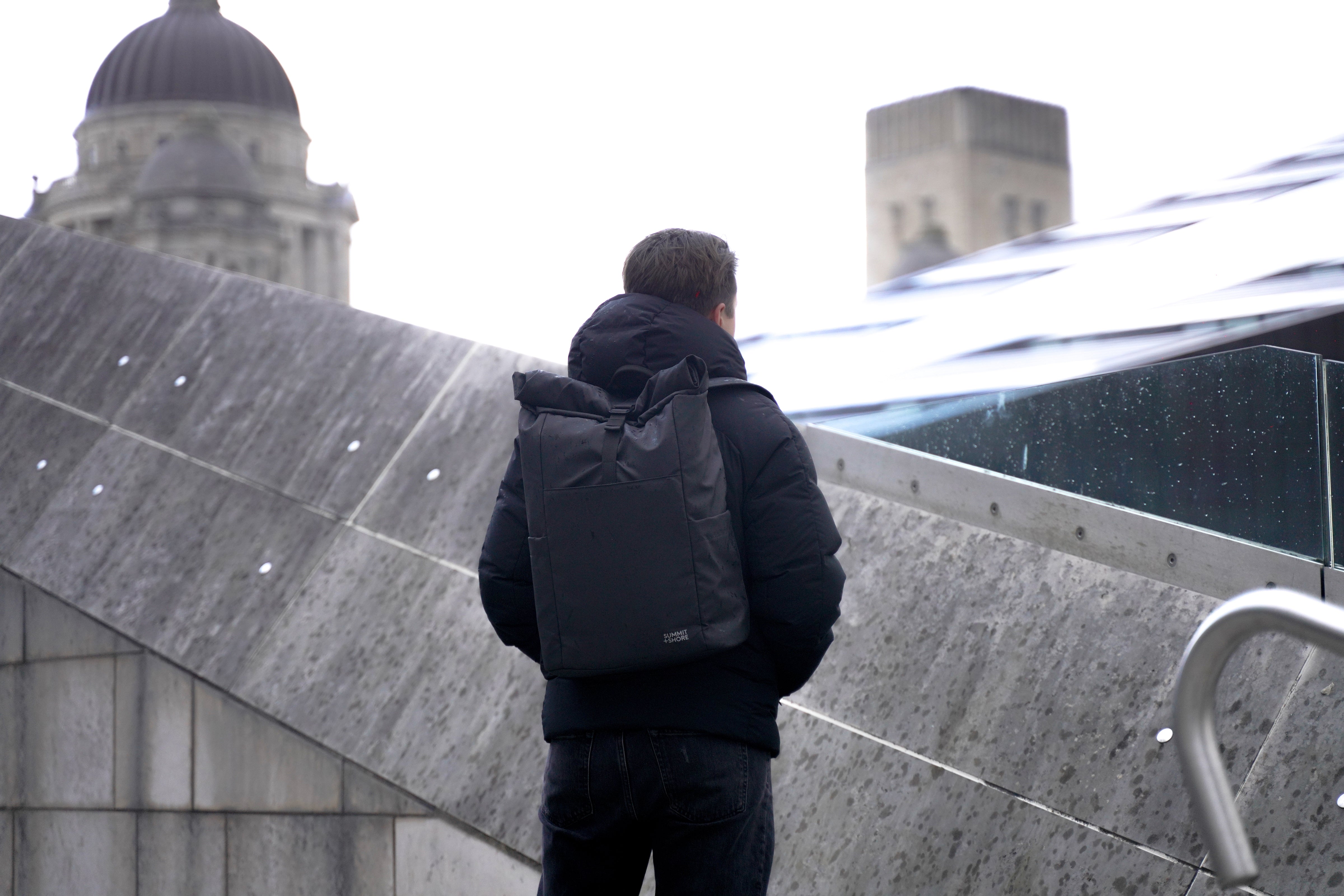 Man Looking Out Over City with Summit and Shore Roll Top Backpack